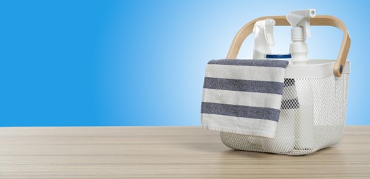 Image of Eco-friendly cleaning products in basket on wooden table against light blue gradient background, space for text