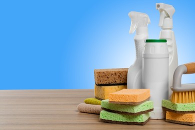 Image of Eco-friendly cleaning products on wooden table against light blue gradient background, space for text