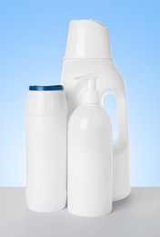 Image of Bottles of cleaning products on white table against light blue gradient background