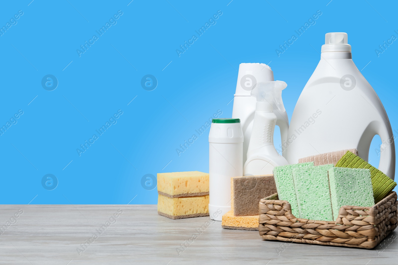 Image of Eco-friendly cleaning products on wooden table against light blue gradient background, space for text