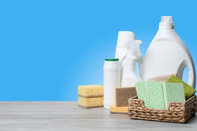 Image of Eco-friendly cleaning products on wooden table against light blue gradient background, space for text