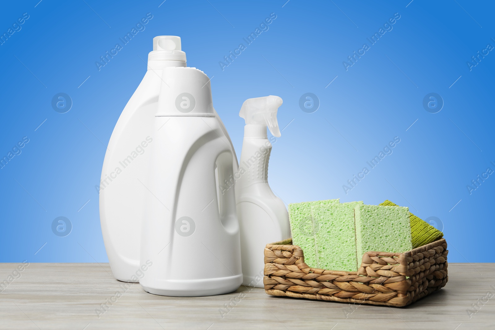 Image of Eco-friendly cleaning products on wooden table against light blue gradient background