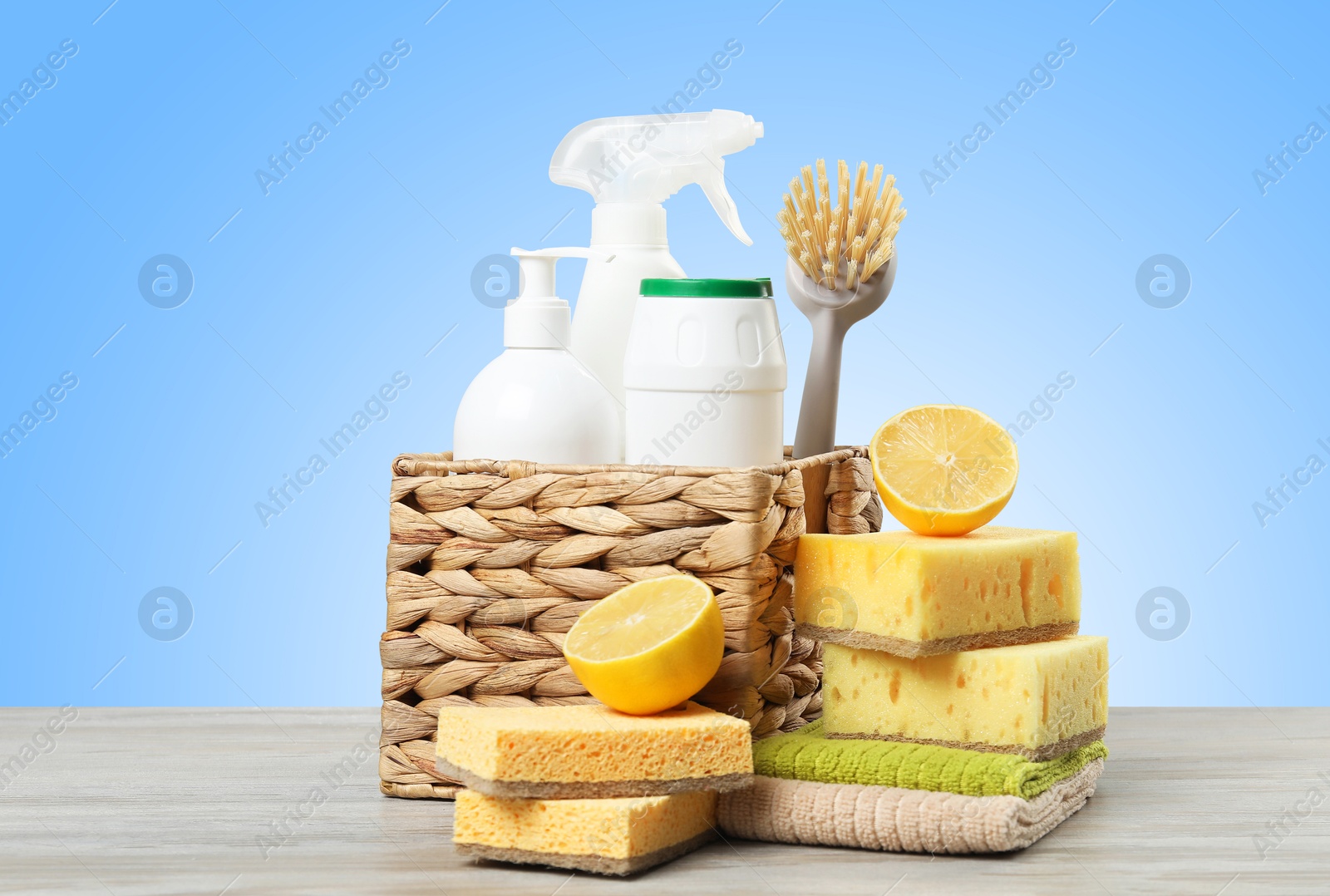 Image of Eco-friendly cleaning products on wooden table against light blue gradient background