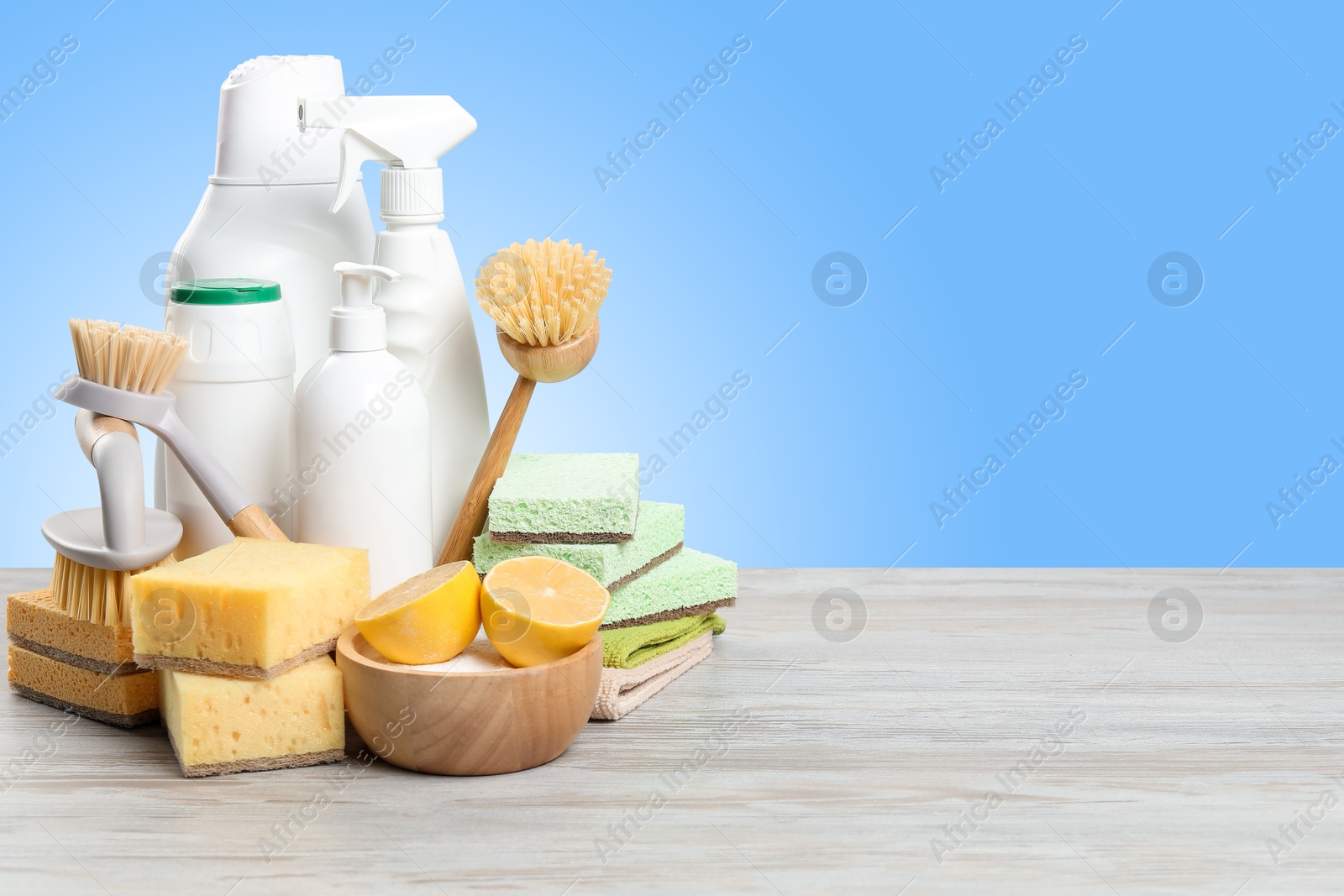 Image of Eco-friendly cleaning products on wooden table against light blue gradient background, space for text