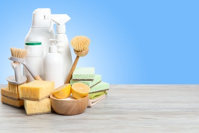 Image of Eco-friendly cleaning products on wooden table against light blue gradient background, space for text