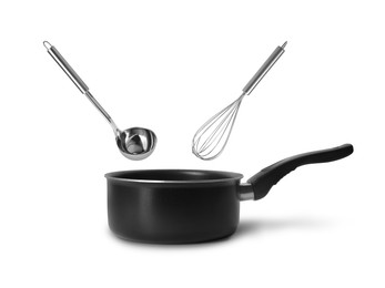 Image of Ladle and whisk in air over saucepan on white background