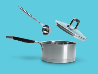 Image of Ladle and lid in air over saucepan on light blue background