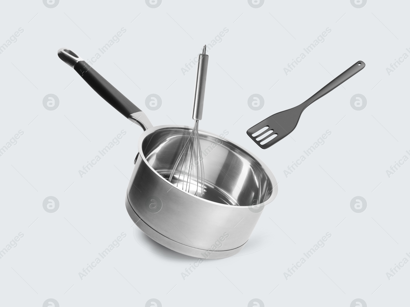 Saucepan, slotted spatula and whisk in air on white background Image of Saucepan, slotted spatula and whisk in air on white background