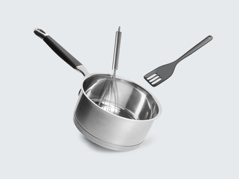 Image of Saucepan, slotted spatula and whisk in air on white background