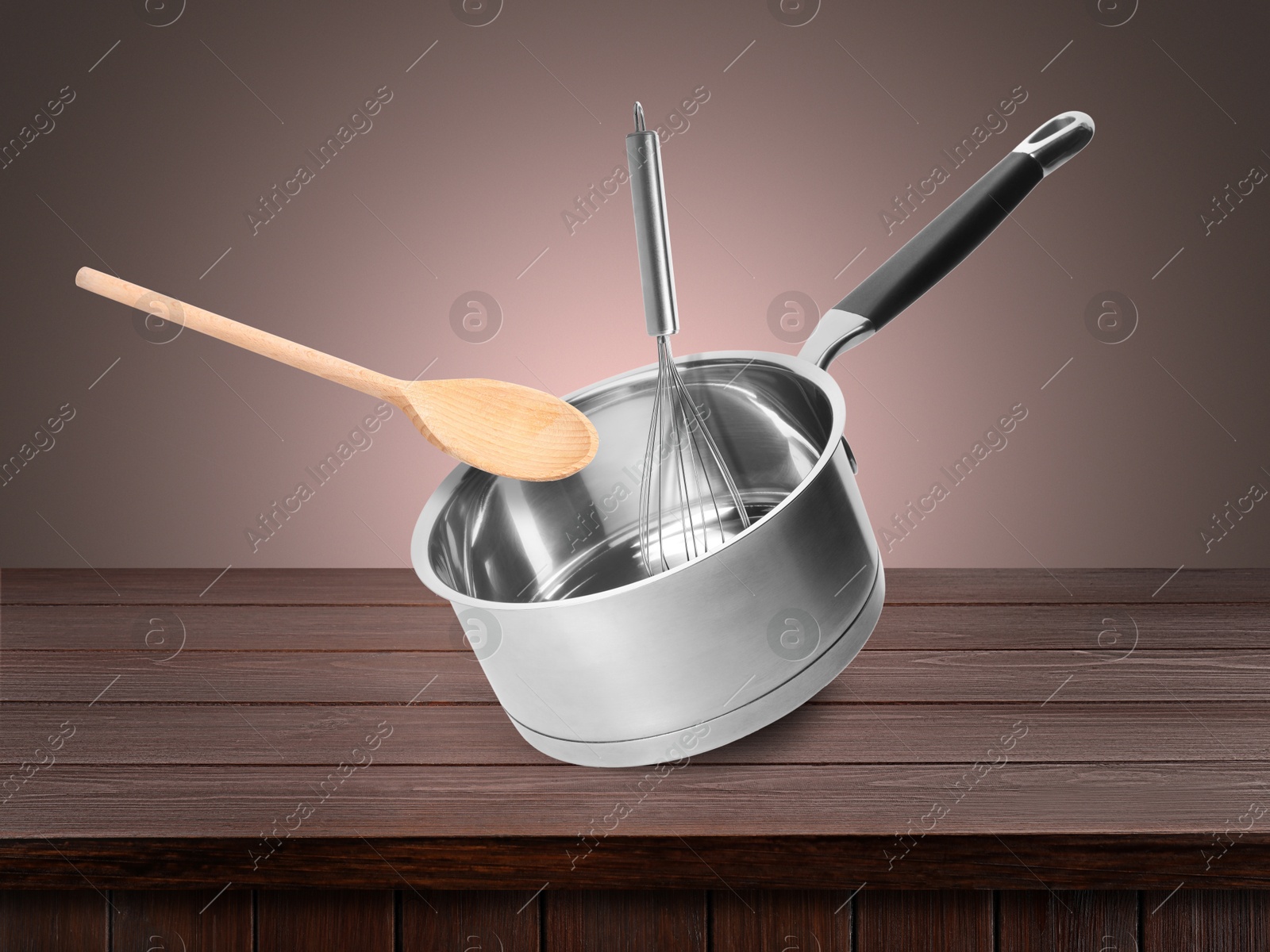 Saucepan, wooden spoon and whisk in air on pale brown background Image of Saucepan, wooden spoon and whisk in air on pale brown background