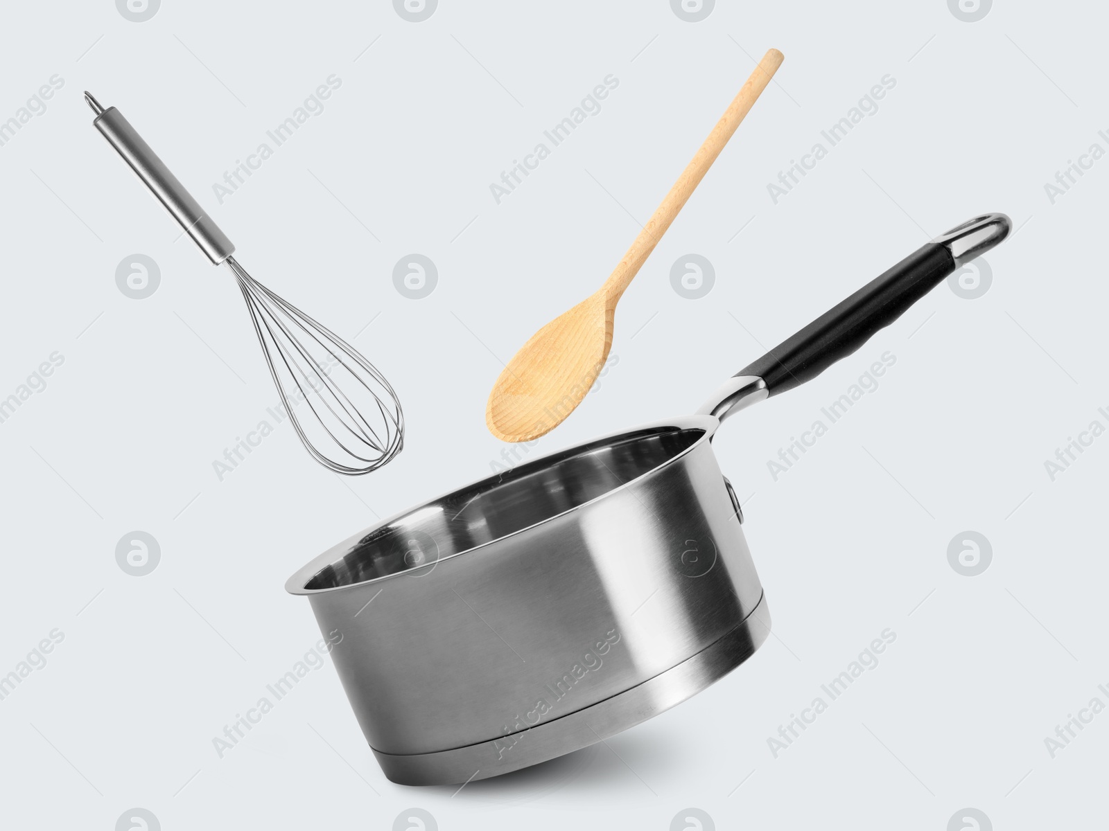 Saucepan, whisk and wooden spoon in air on white background Image of Saucepan, whisk and wooden spoon in air on white background