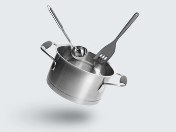 Image of Saucepan, ladle and slotted spatula in air on white background