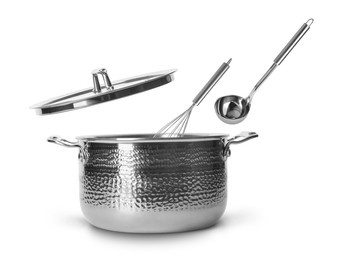 Image of Ladle and whisk in air over saucepan on white background