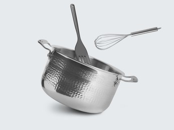 Image of Saucepan, whisk and slotted spatula in air on white background