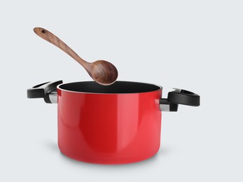 Image of Wooden ladle over saucepan on white background