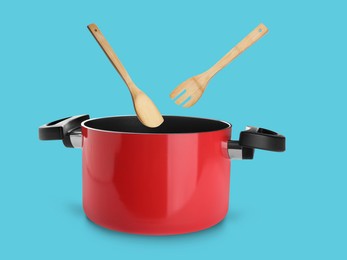 Image of Wooden spoon and turner over saucepan on light blue background