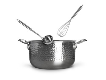 Image of Ladle and whisk in air over saucepan on white background