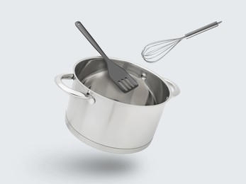 Image of Saucepan, slotted spatula and whisk in air on white background