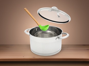 Image of Ladle and lid over saucepan on wooden table against pale brown background