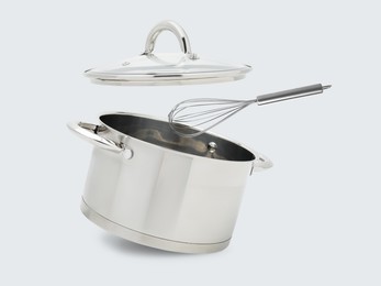 Image of Saucepan, whisk and lid in air on white background