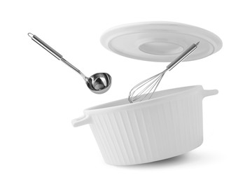 Saucepan, ladle and whisk in air on white background