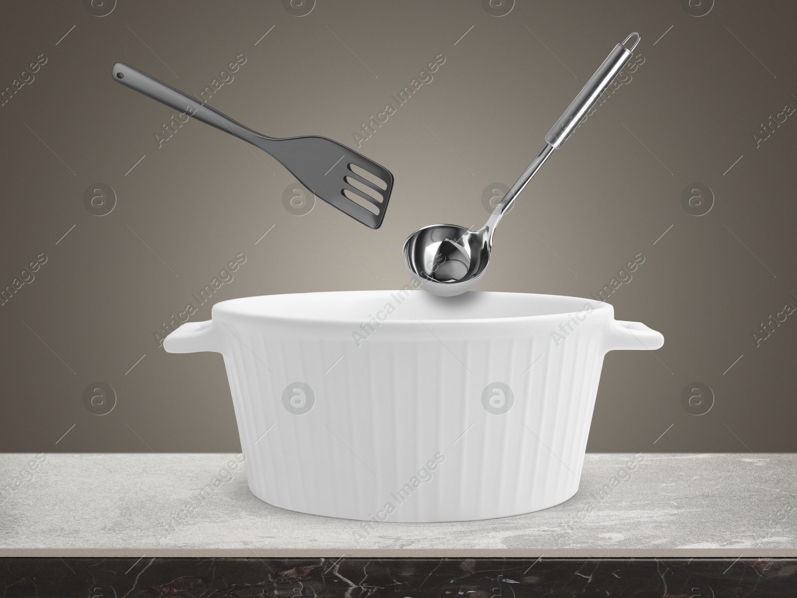 Image of Slotted spatula and ladle in air over saucepan on table against grey background