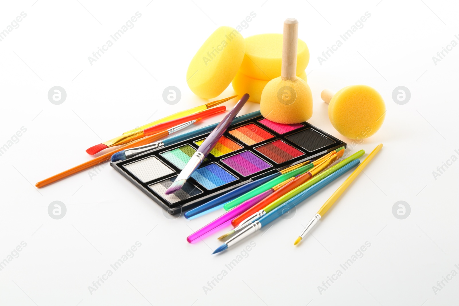 Photo of Bright face paint palette, brushes and sponges isolated on white