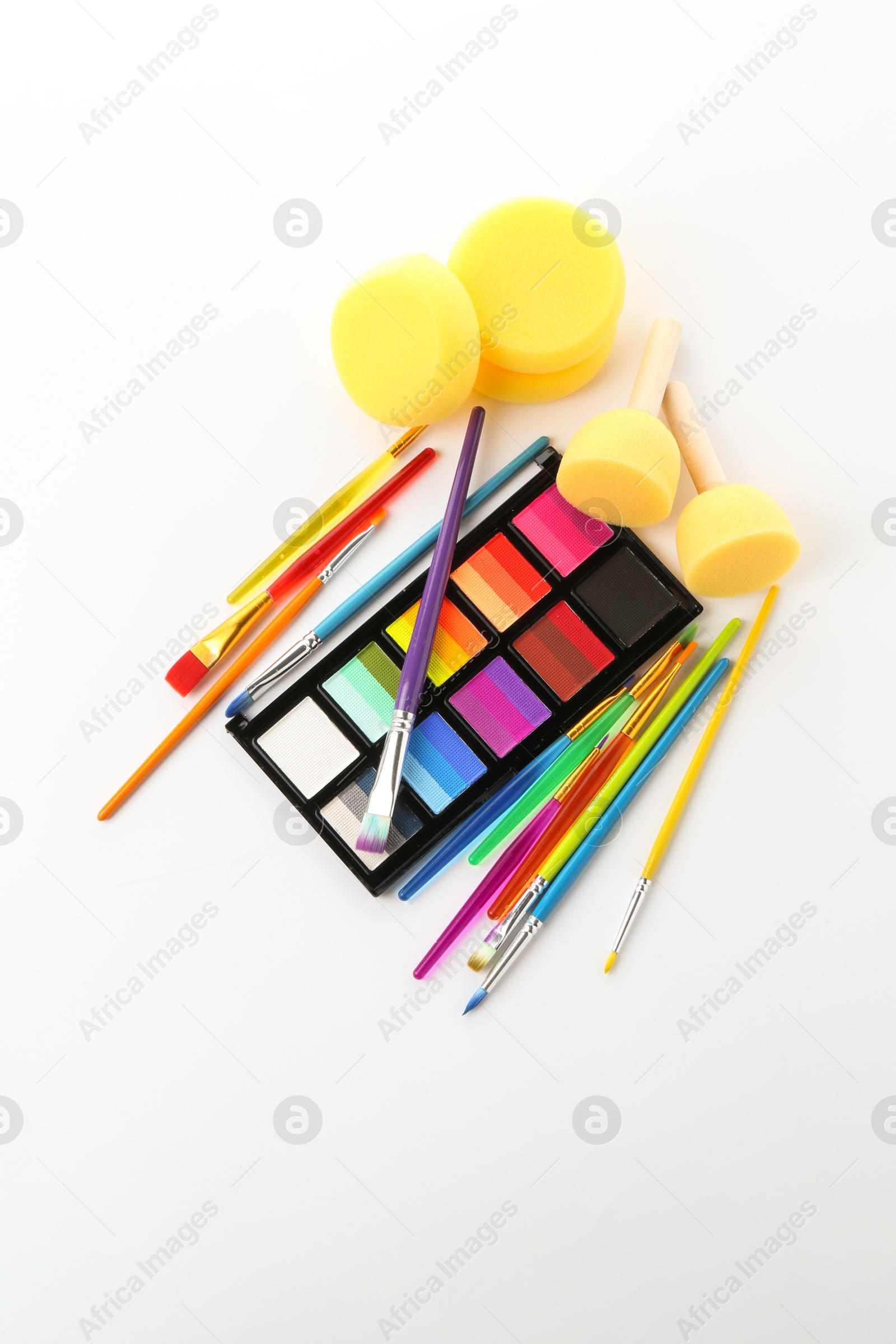 Bright face paint palette, brushes and sponges isolated on white, top view Photo of Bright face paint palette, brushes and sponges isolated on white, top view