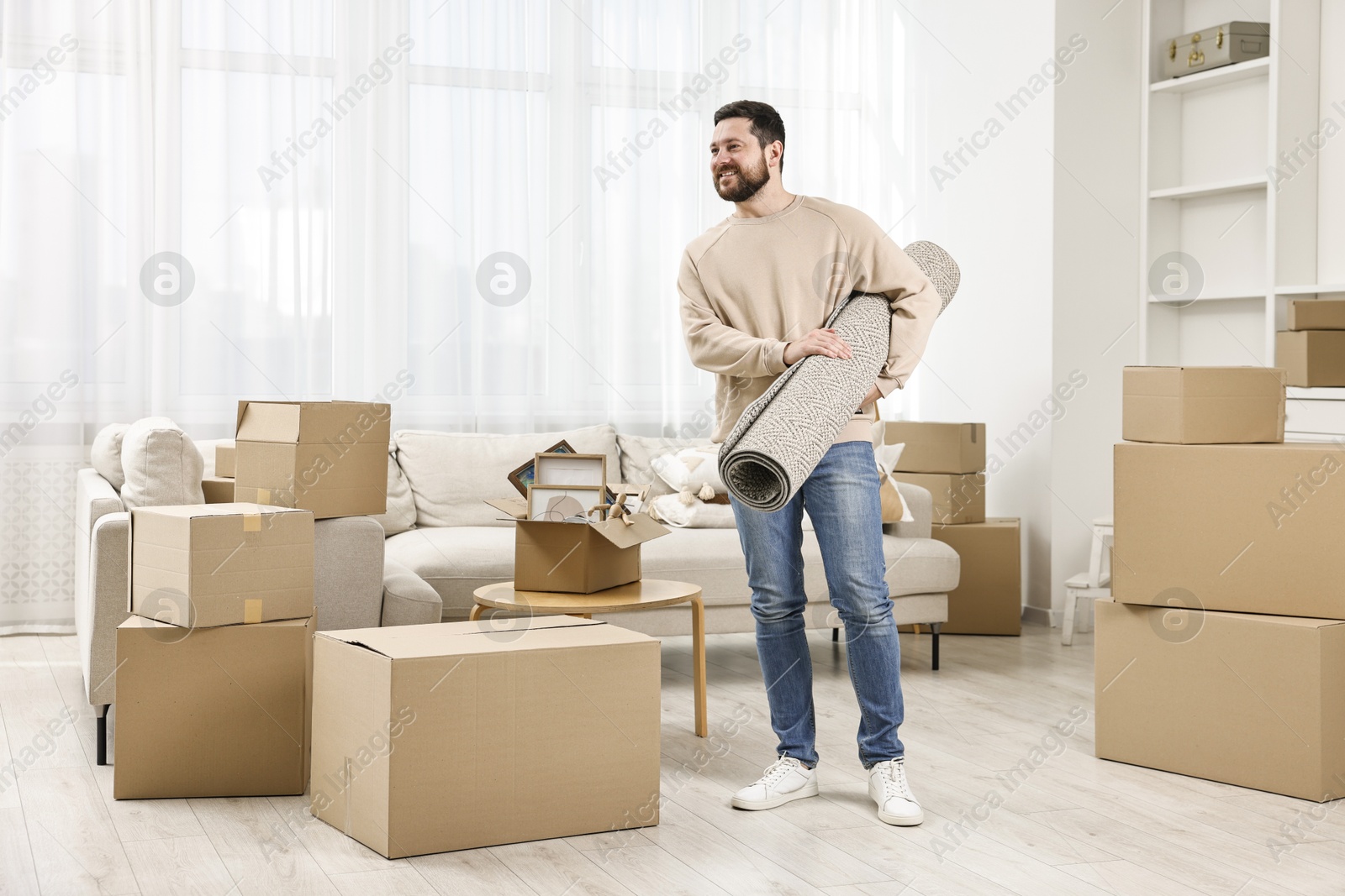 Photo of Moving day. Happy man with rug in his new home