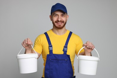 Professional painter with buckets of paint on light grey background