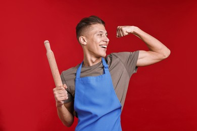 Photo of Happy man with rolling pin showing strength on red background