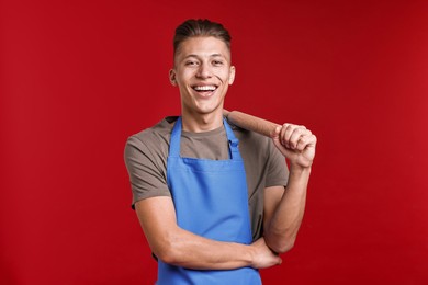 Happy man with rolling pin on red background