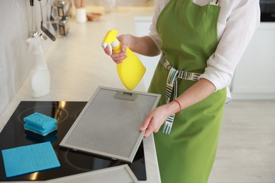 Photo of Woman cleaning filter of kitchen hood with detergent indoors, closeup