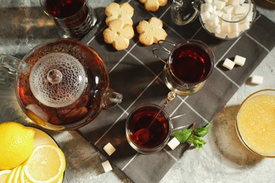 Photo of Glasses of tea in metal holders served on grey textured table, flat lay