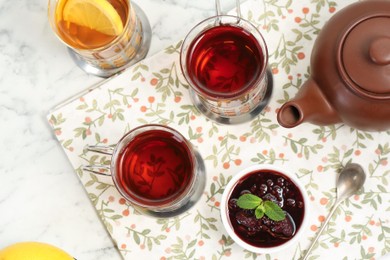 Glasses of tea in metal holders served on white marble table, flat lay