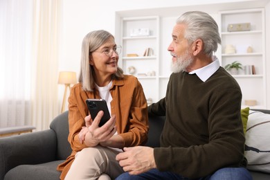 Photo of Cute elderly couple with smartphone on sofa at home