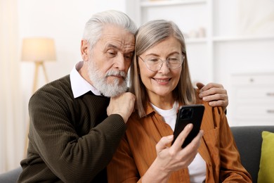 Cute elderly couple with smartphone at home