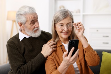 Cute elderly couple with smartphone at home