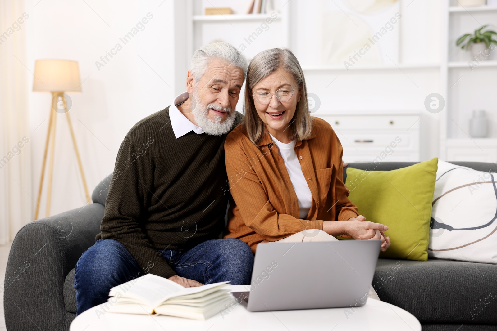 Photo of Happy elderly couple with laptop on sofa at home