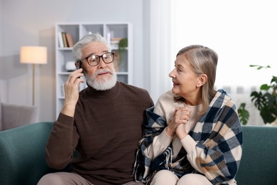 Cute elderly couple on sofa at home