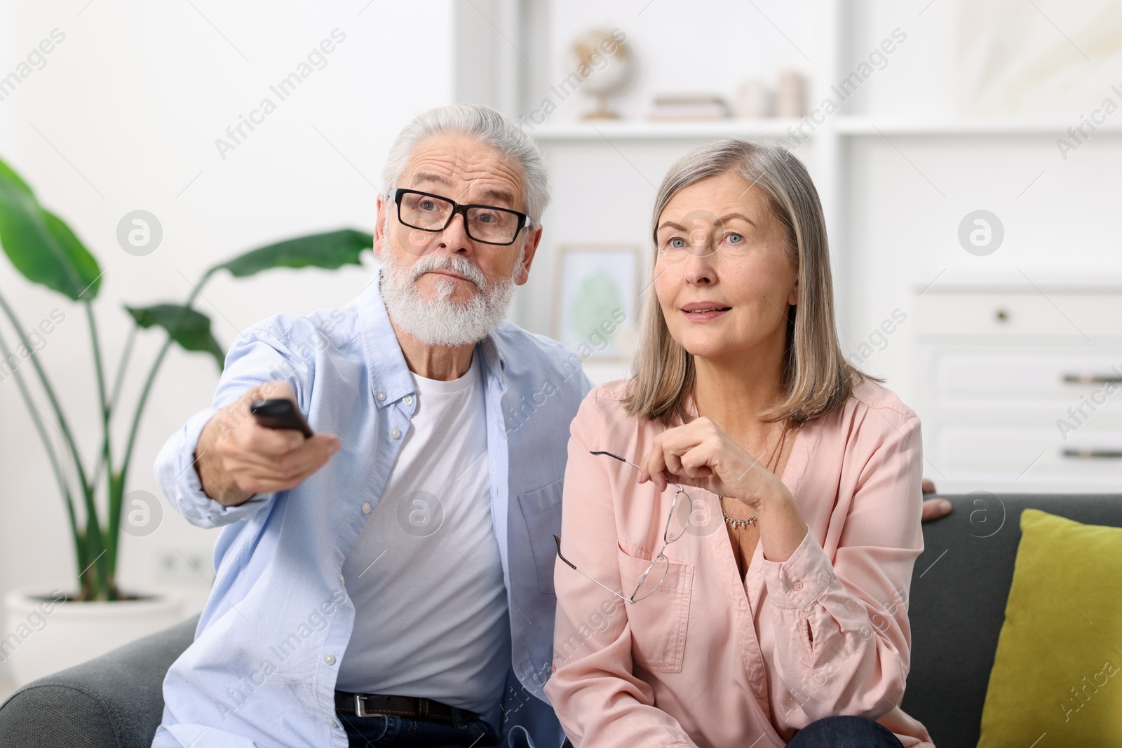 Photo of Cute elderly couple watching tv on sofa at home