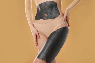 Photo of Woman doing spa body wraps on beige background, closeup