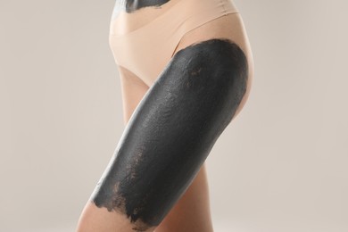 Woman doing spa body wraps on her leg against light grey background, closeup