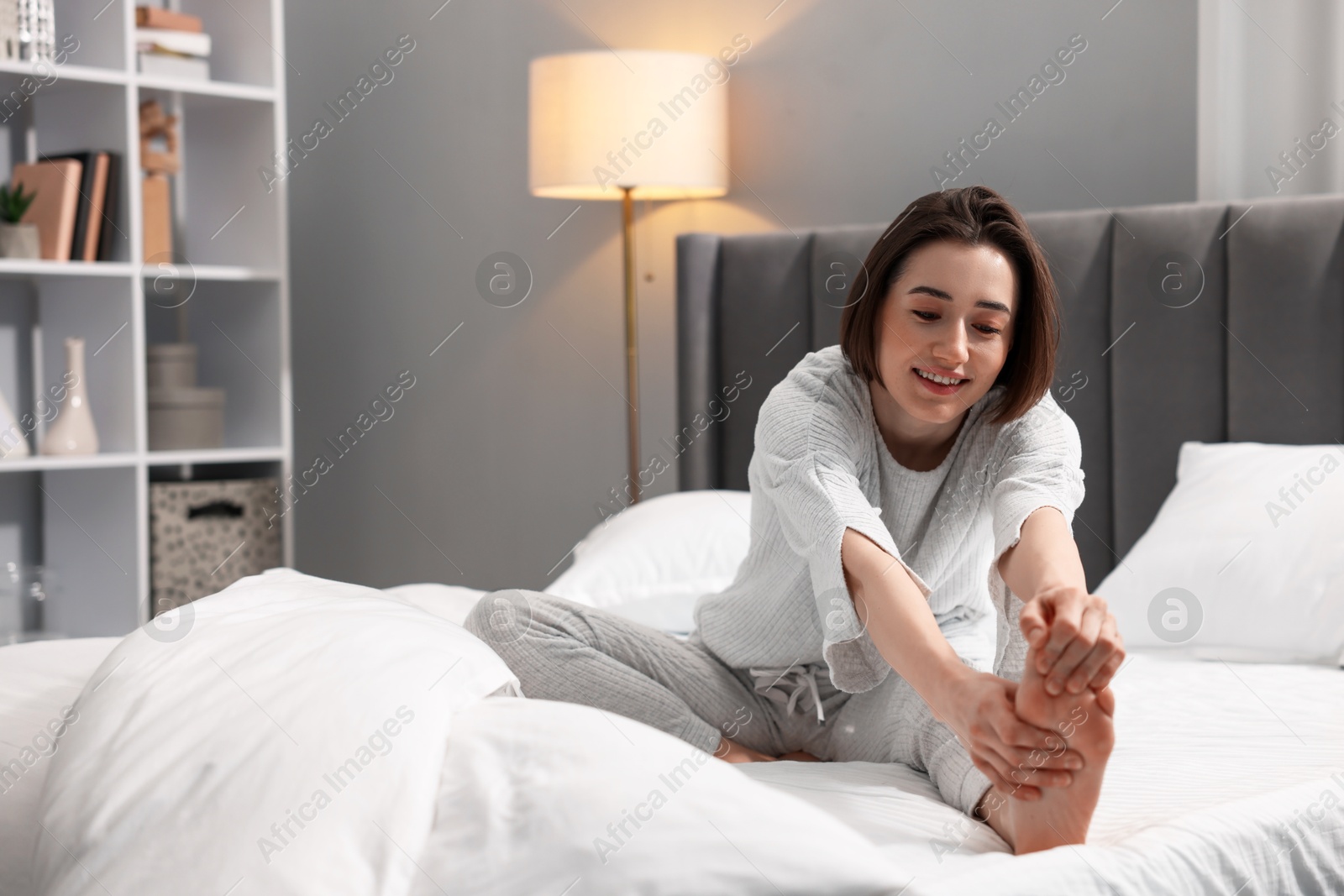 Photo of Young woman exercising on bed at home. Morning routine