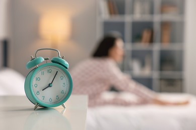 Photo of Young woman exercising on bed at home, focus on alarm clock. Morning routine