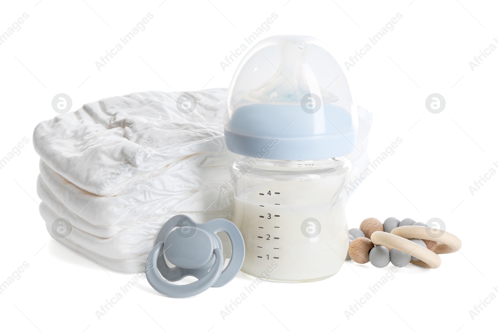 Photo of Feeding bottle with milk, diapers, teether and pacifier isolated on white