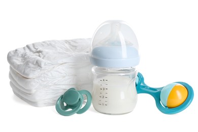 Photo of Feeding bottle with milk, diapers, baby rattle and pacifier isolated on white