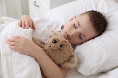 Bedtime. Cute boy sleeping with his teddy bear in bed