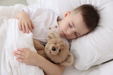 Photo of Bedtime. Cute boy sleeping with his teddy bear in bed