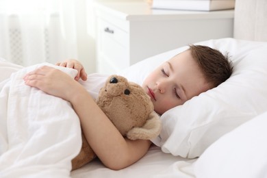 Bedtime. Cute boy sleeping with his teddy bear in bed